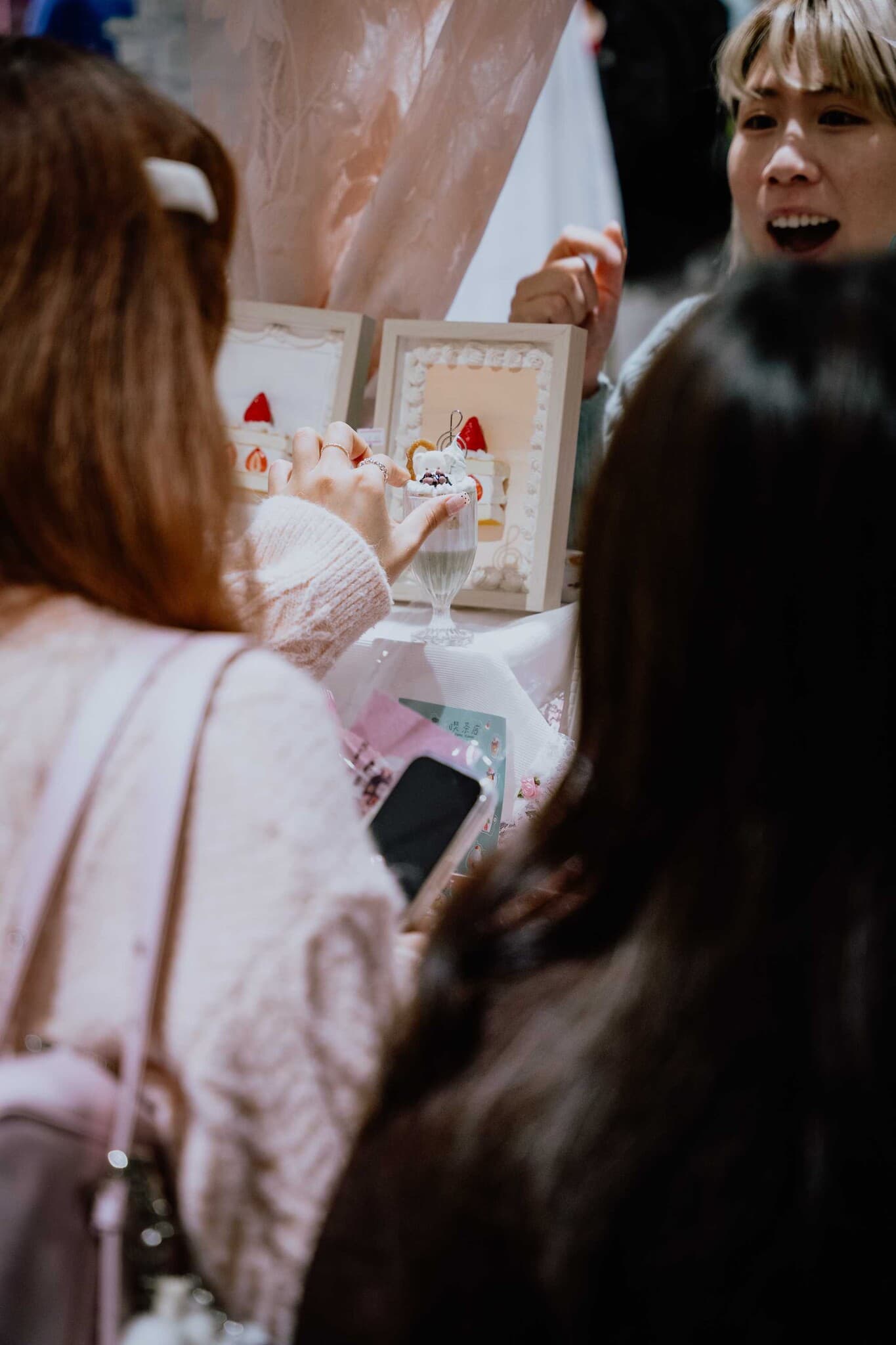 A shopper admiring framed dessert-themed artwork with the stallholder