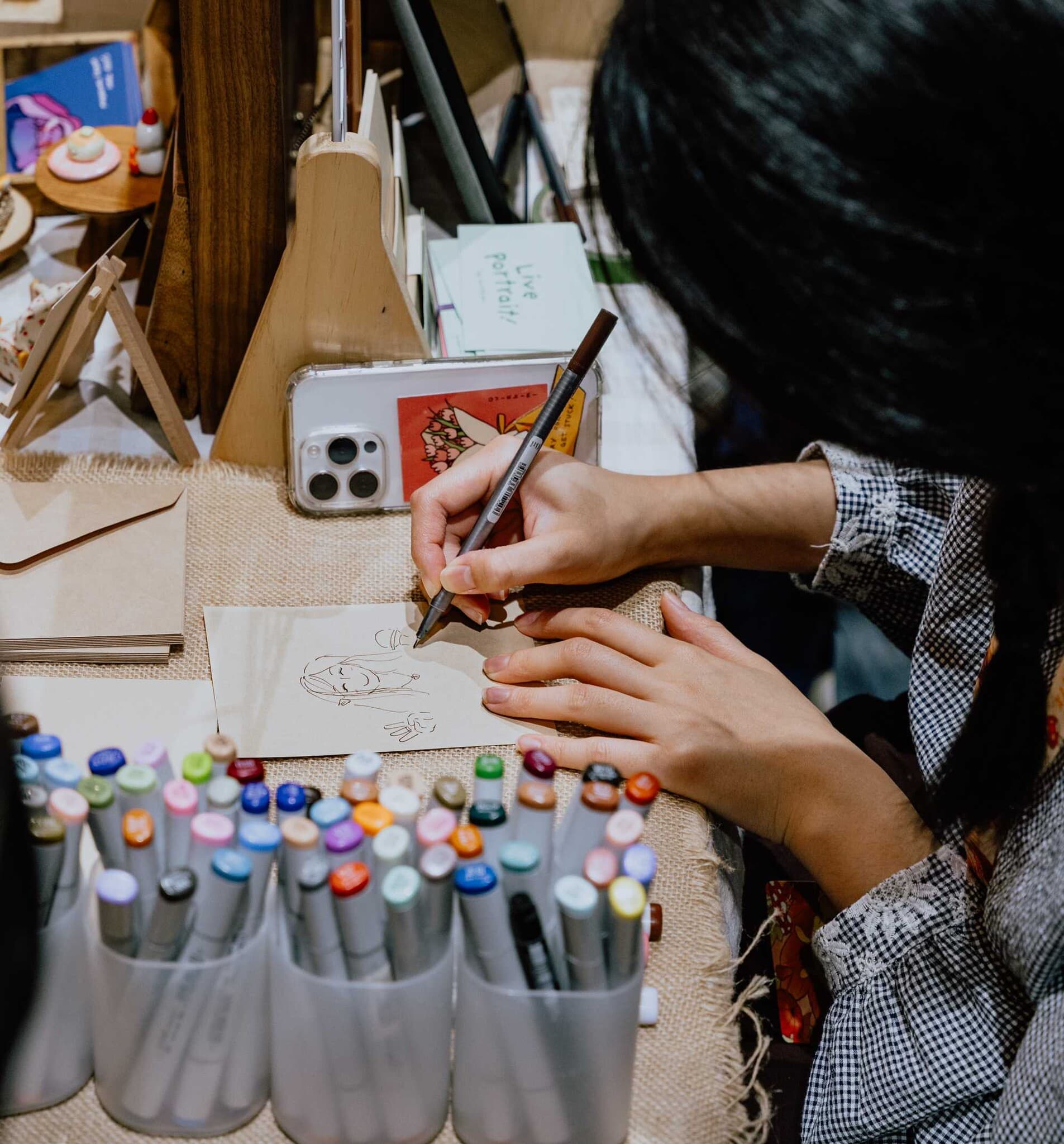 An artist sketching a live commission at their stall