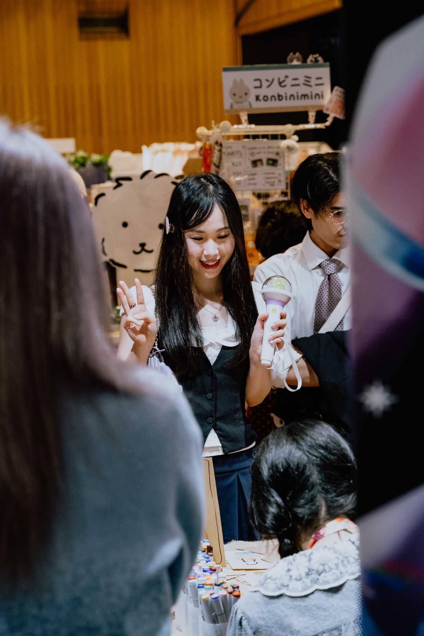 A smiling stallholder flashing a peace sign at her stall